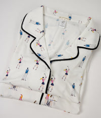 Folded white shirt with black trim and tennis-themed pattern on a light gray background