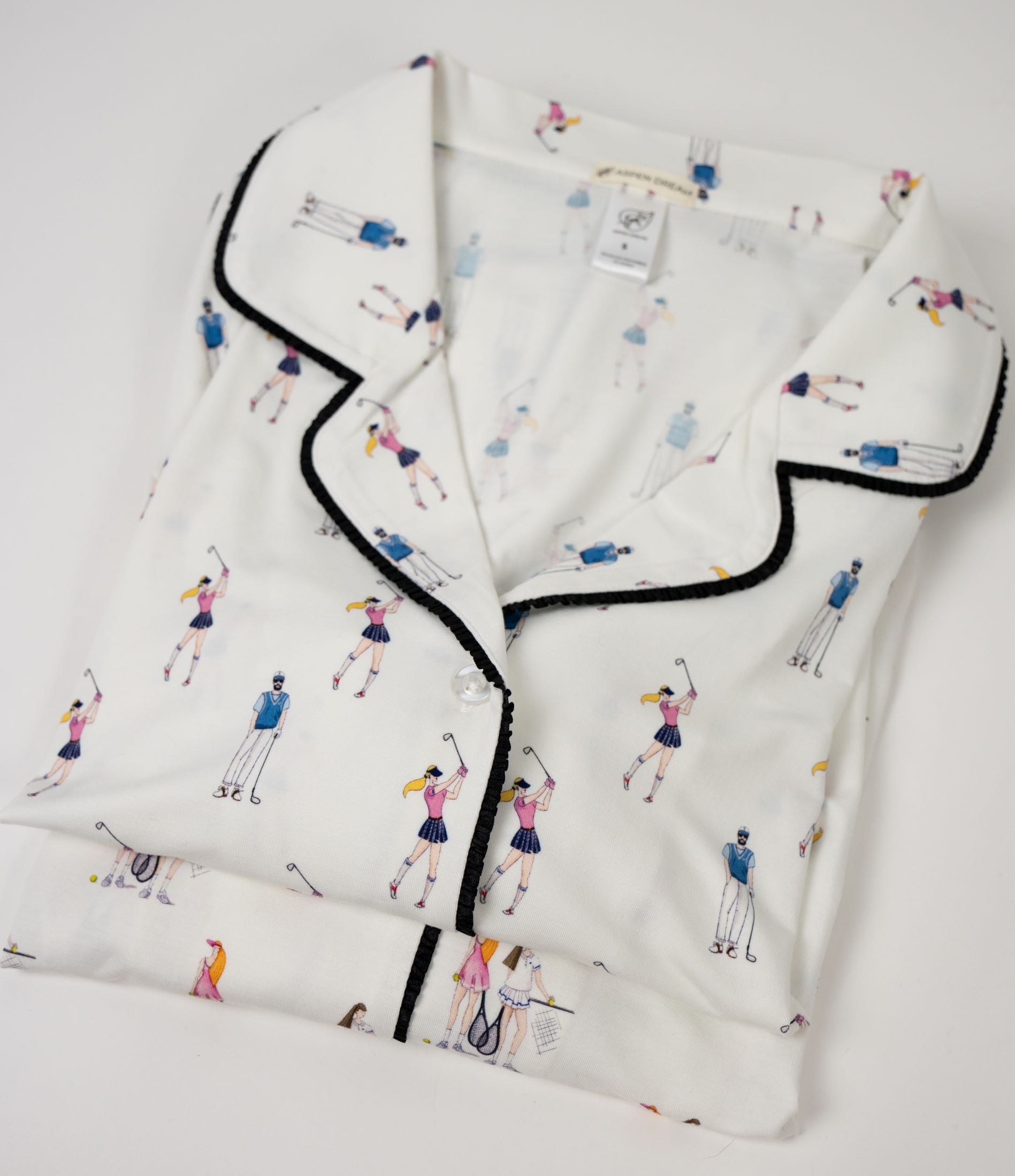 Folded white shirt with black trim and tennis-themed pattern on a light gray background