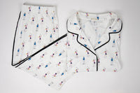 White pajama set with black-trimmed edges and small colorful patterns on a light gray background