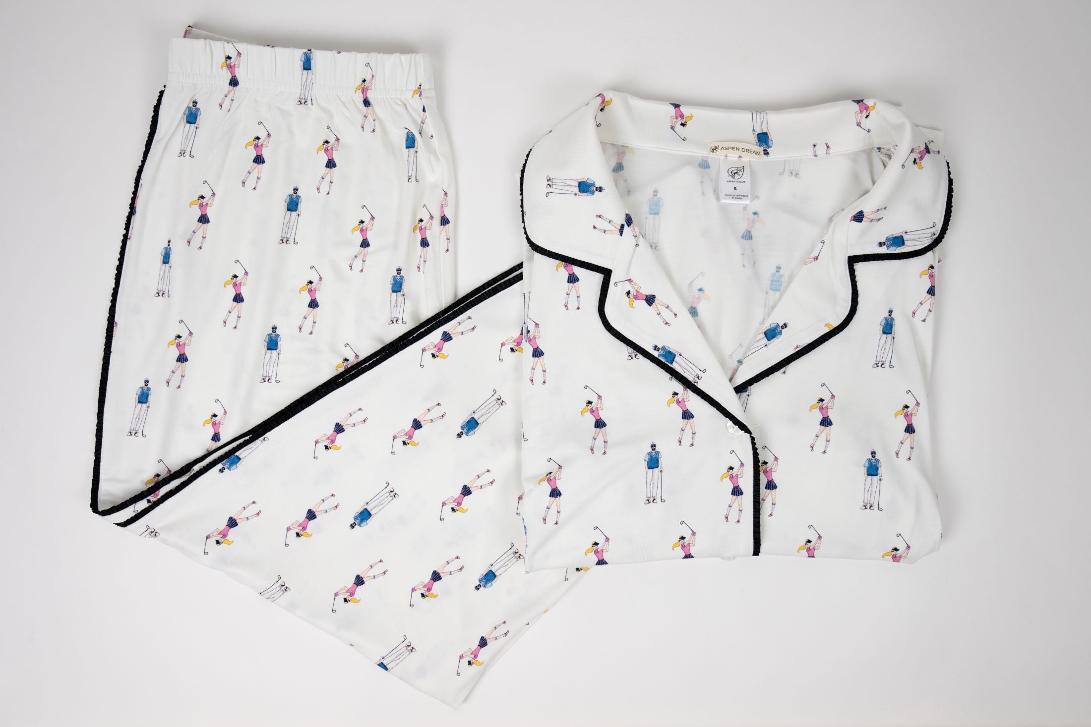 White pajama set with black-trimmed edges and small colorful patterns on a light gray background