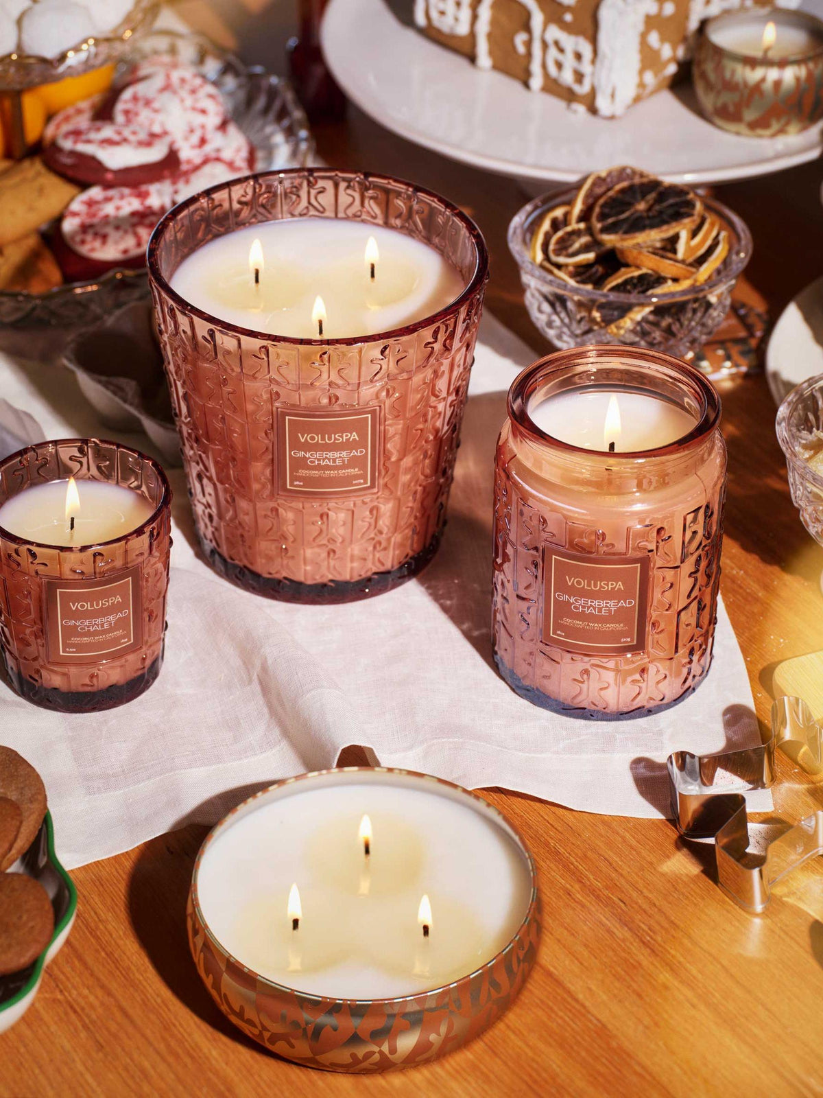 Voluspa Gingerbread Chalet candle collection with a lit 3-wick tin candle and glass jar candles