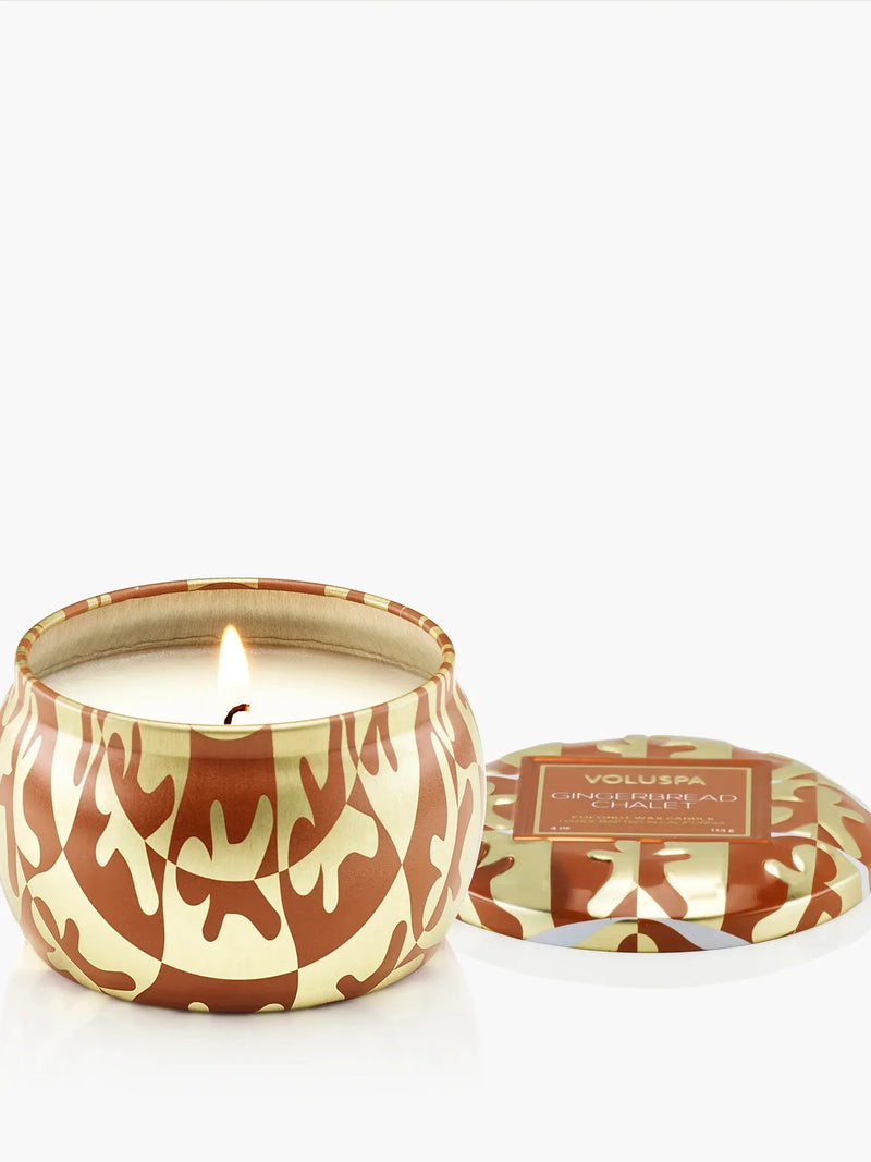 Voluspa Gingerbread Chalet Mini Tin Candle, lit candle in a brown and cream tin with the lid beside it